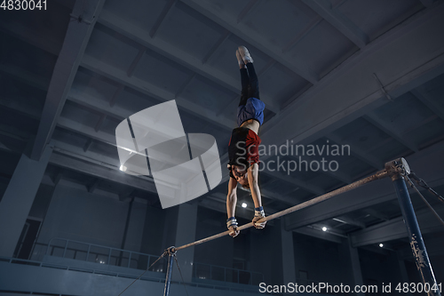 Image of Little male gymnast training in gym, flexible and active