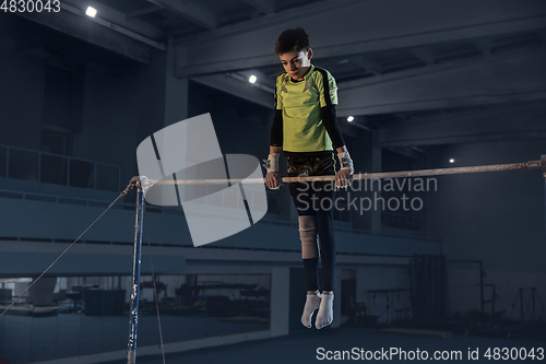 Image of Little male gymnast training in gym, flexible and active