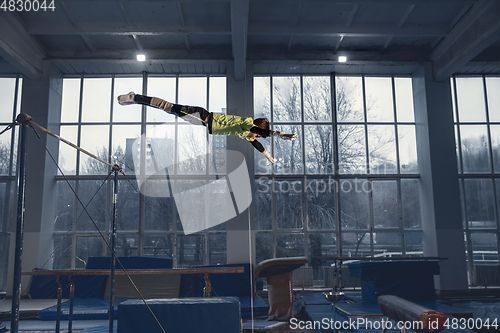 Image of Little male gymnast training in gym, flexible and active