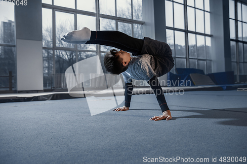 Image of Little male gymnast training in gym, flexible and active