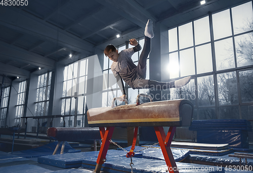 Image of Little male gymnast training in gym, flexible and active