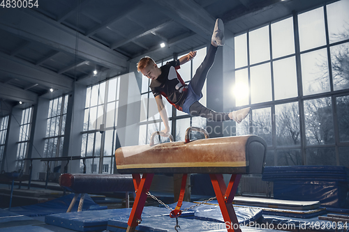 Image of Little male gymnast training in gym, flexible and active