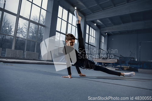 Image of Little male gymnast training in gym, flexible and active