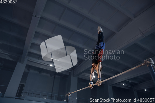 Image of Little male gymnast training in gym, flexible and active