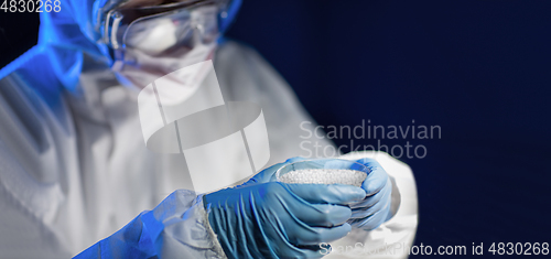 Image of close up of scientist with chemical in petri dish