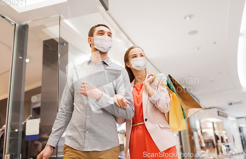 Image of couple in medical masks with shopping bags in mall