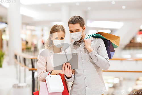 Image of couple in masks with tablet pc in shopping mall