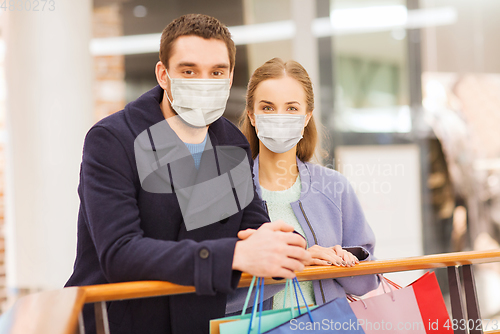 Image of couple in medical masks with shopping bags in mall