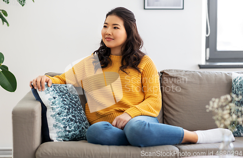 Image of asian young woman sitting on sofa at home