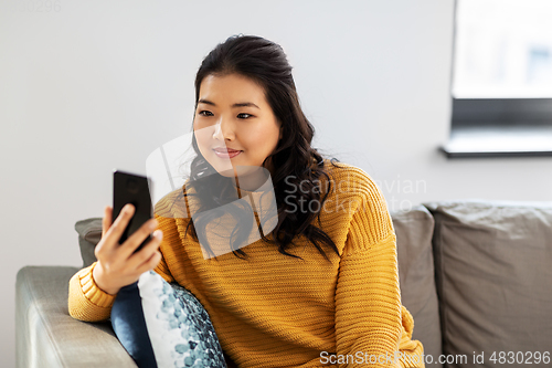 Image of happy asian young woman with smartphone at home