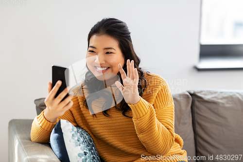 Image of woman with smartphone having video call at home