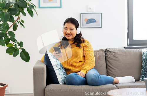 Image of asian woman with headphones and smartphone at home