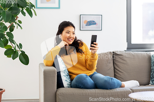 Image of asian woman with earphones and smartphone at home