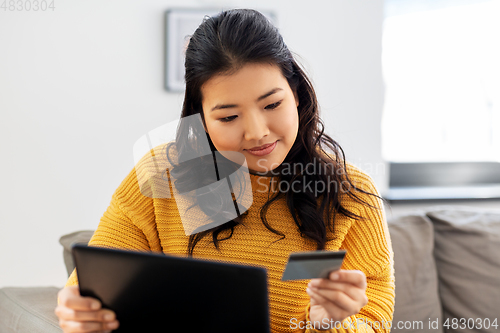 Image of asian woman with tablet pc and credit card at home