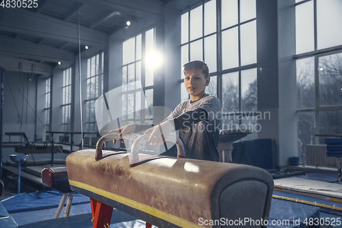 Image of Little male gymnast training in gym, flexible and active