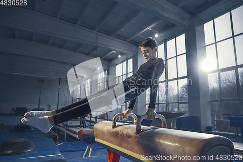 Image of Little male gymnast training in gym, flexible and active