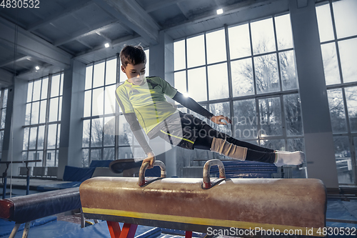 Image of Little male gymnast training in gym, flexible and active