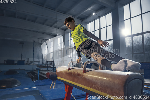 Image of Little male gymnast training in gym, flexible and active