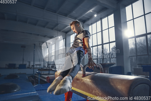 Image of Little male gymnast training in gym, flexible and active