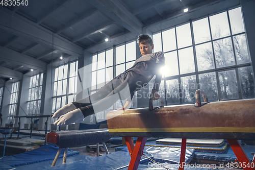 Image of Little male gymnast training in gym, flexible and active