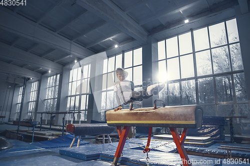 Image of Little male gymnast training in gym, flexible and active