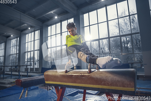 Image of Little male gymnast training in gym, flexible and active