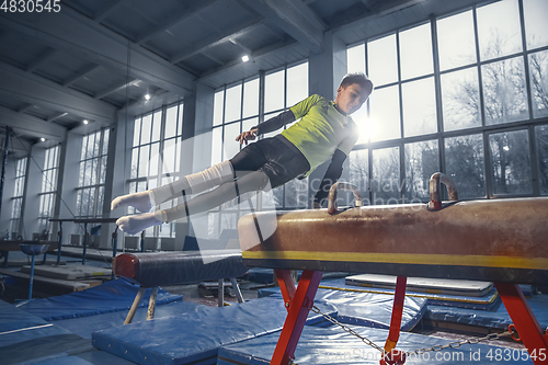 Image of Little male gymnast training in gym, flexible and active