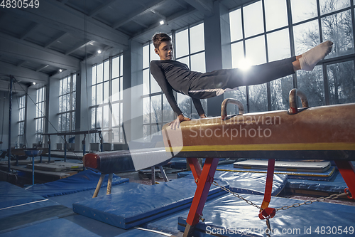 Image of Little male gymnast training in gym, flexible and active