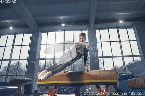 Image of Little male gymnast training in gym, flexible and active