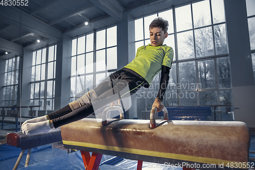 Image of Little male gymnast training in gym, flexible and active