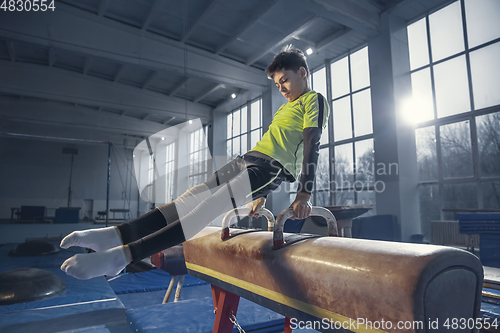 Image of Little male gymnast training in gym, flexible and active