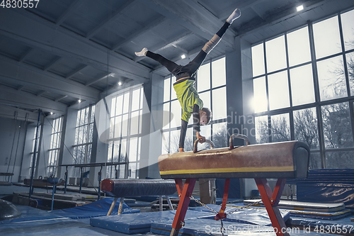 Image of Little male gymnast training in gym, flexible and active