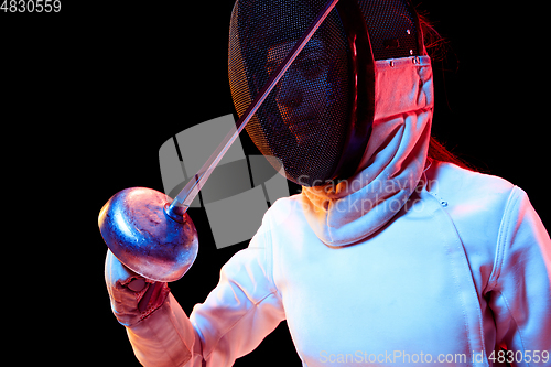 Image of Teen girl in fencing costume with sword in hand isolated on black background