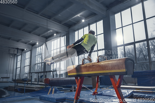 Image of Little male gymnast training in gym, flexible and active