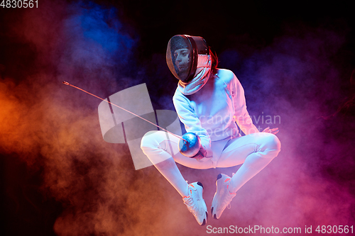 Image of Teen girl in fencing costume with sword in hand isolated on black background