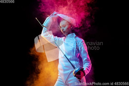 Image of Teen girl in fencing costume with sword in hand isolated on black background