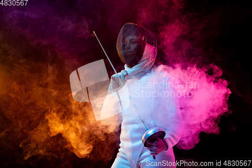 Image of Teen girl in fencing costume with sword in hand isolated on black background