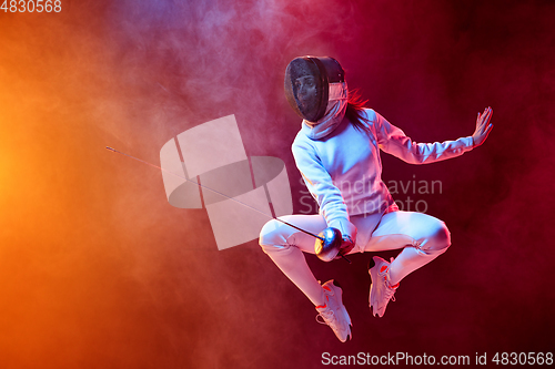 Image of Teen girl in fencing costume with sword in hand isolated on black background