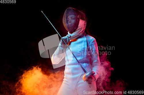 Image of Teen girl in fencing costume with sword in hand isolated on black background