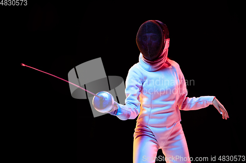 Image of Teen girl in fencing costume with sword in hand isolated on black background