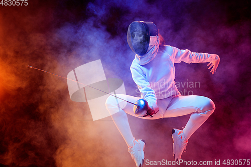 Image of Teen girl in fencing costume with sword in hand isolated on black background