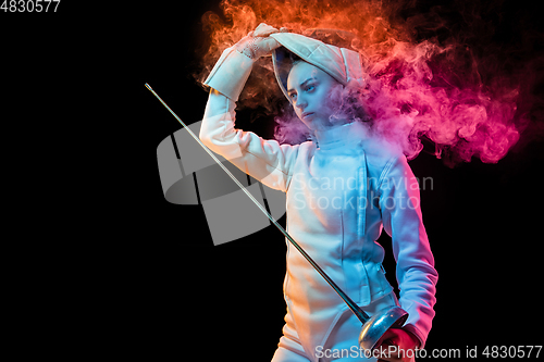 Image of Teen girl in fencing costume with sword in hand isolated on black background