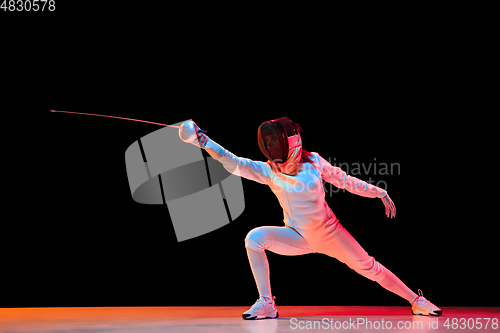 Image of Teen girl in fencing costume with sword in hand isolated on black background