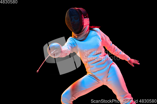 Image of Teen girl in fencing costume with sword in hand isolated on black background