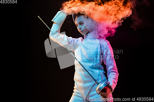 Image of Teen girl in fencing costume with sword in hand isolated on black background