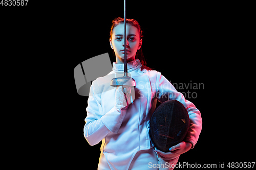 Image of Teen girl in fencing costume with sword in hand isolated on black background