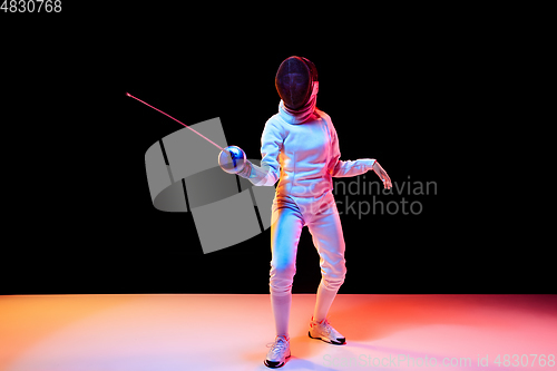 Image of Teen girl in fencing costume with sword in hand isolated on black background