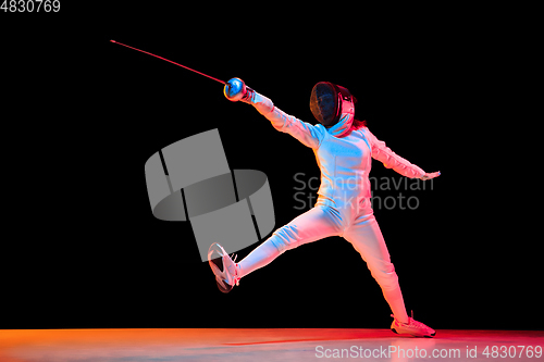 Image of Teen girl in fencing costume with sword in hand isolated on black background