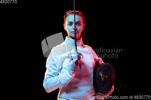 Image of Teen girl in fencing costume with sword in hand isolated on black background