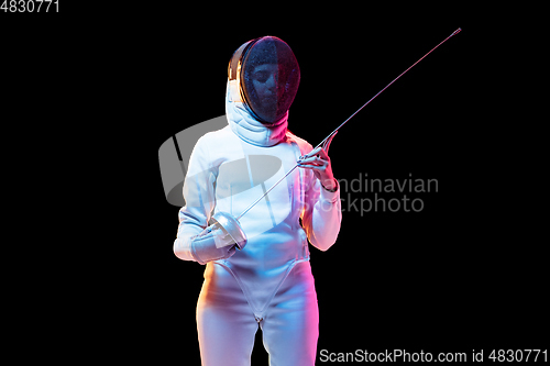 Image of Teen girl in fencing costume with sword in hand isolated on black background